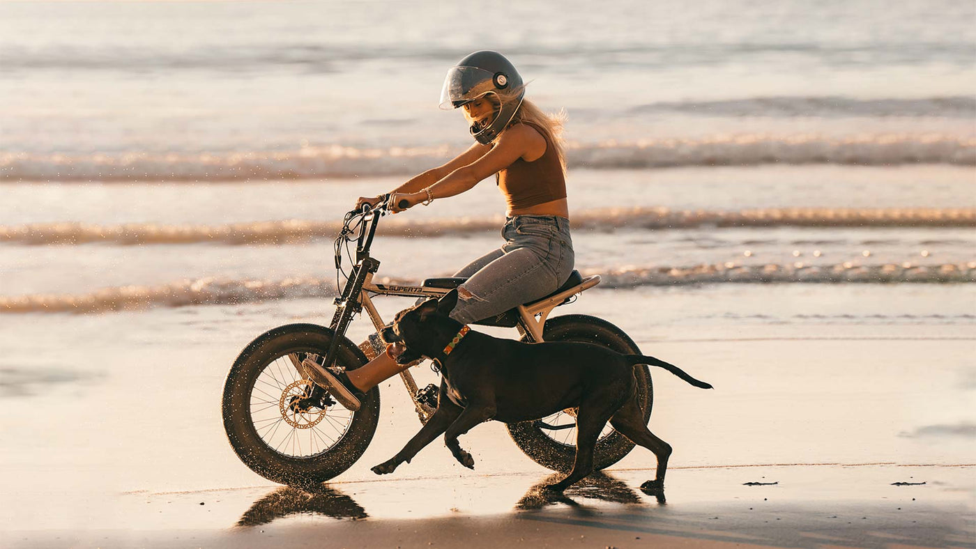 A woman and a dog riding a Super73-ZX along the beach 