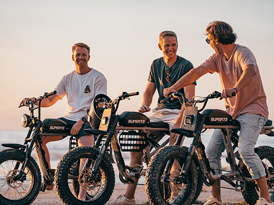 A group of men riding Super73-RX and S2 ebikes on the beach