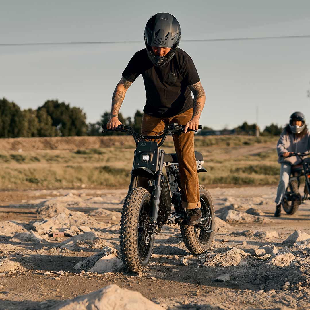 Lifestyle image of a rider riding the R Adventure on a dirt path with his friend and wearing a helmet.
