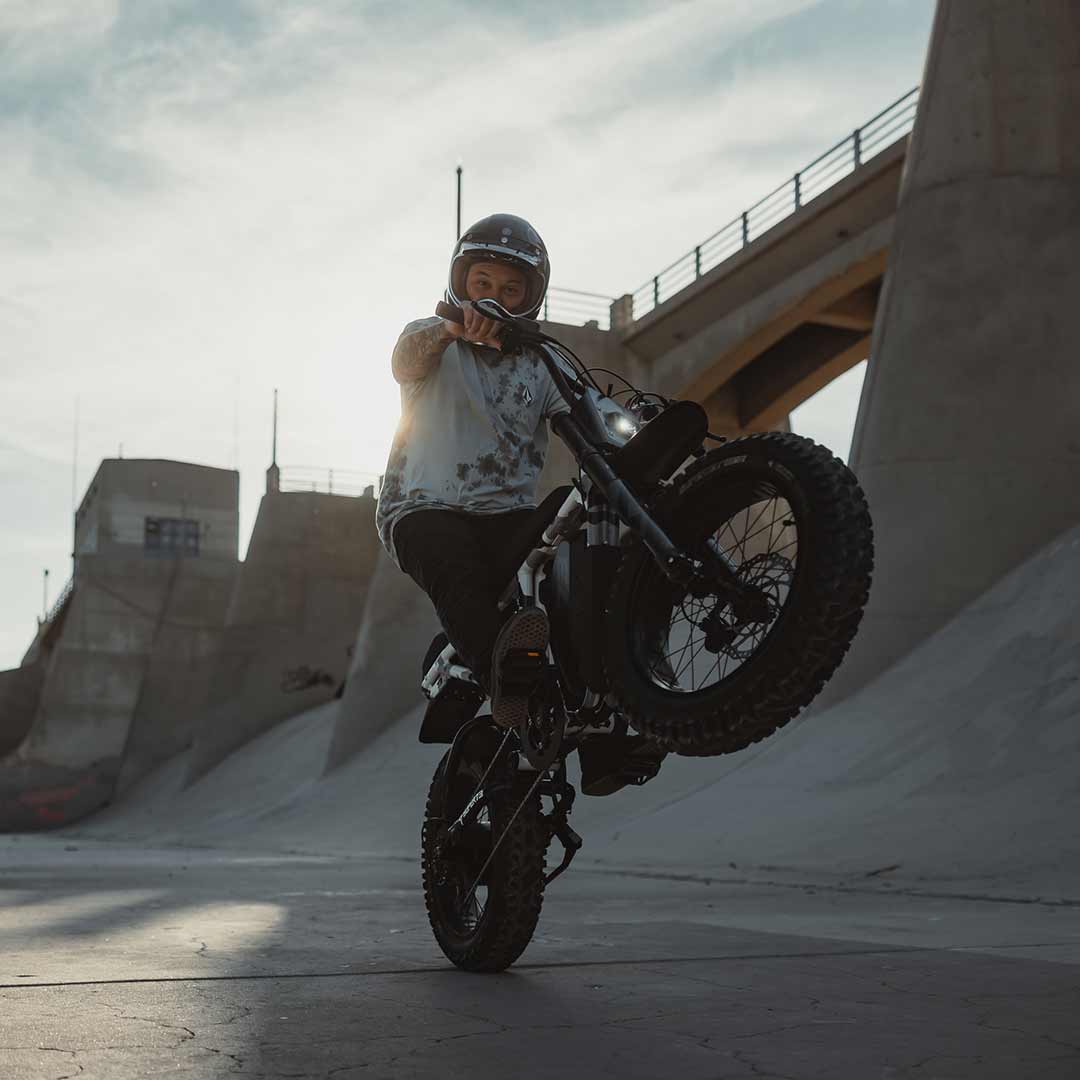 Lifestyle image rider popping a wheelie on their R Adventure and wearing a helmet.