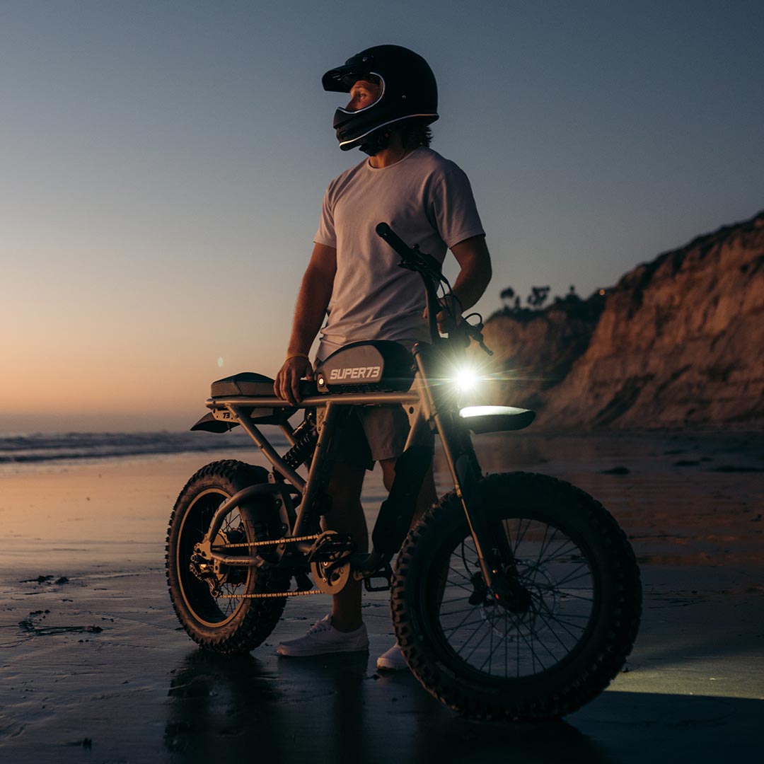 Rider on beach with Super73 RX Mojave ebike looking into the ocean at sunset