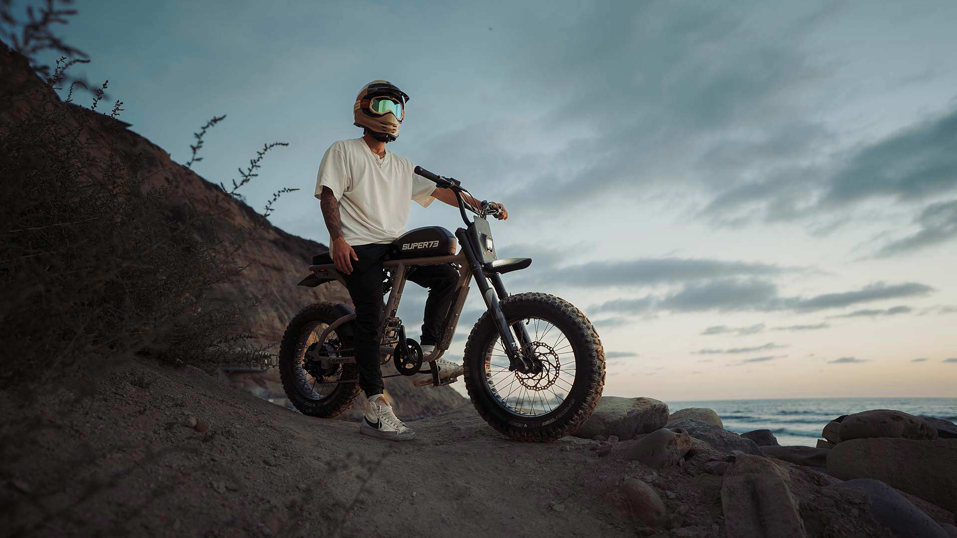 Young man sitting on a Super73 ebike with a helmet on looking into the sunset