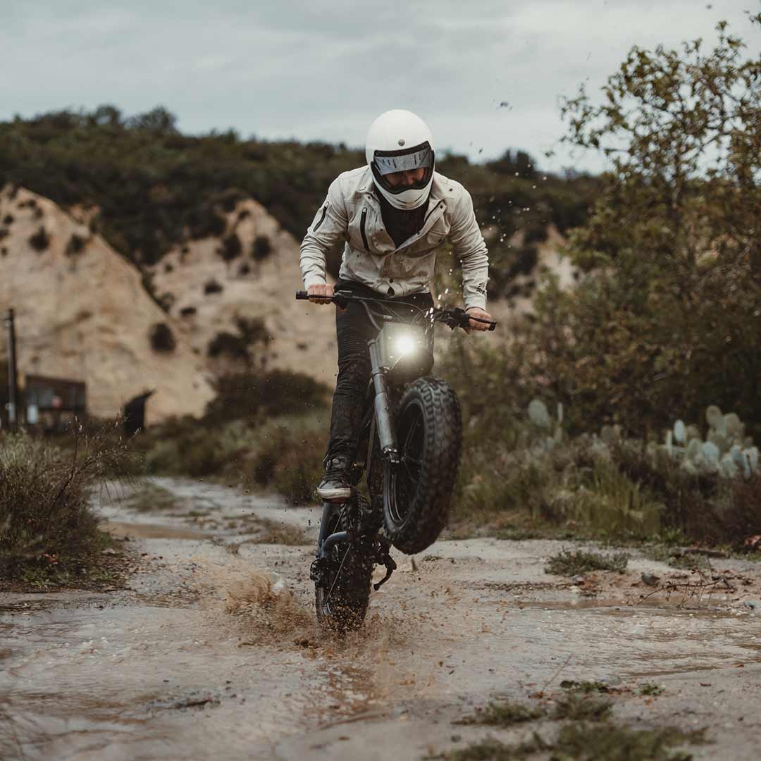 Male rider doing a wheelie on his Z Adventure in the mud while wearing a helmet.