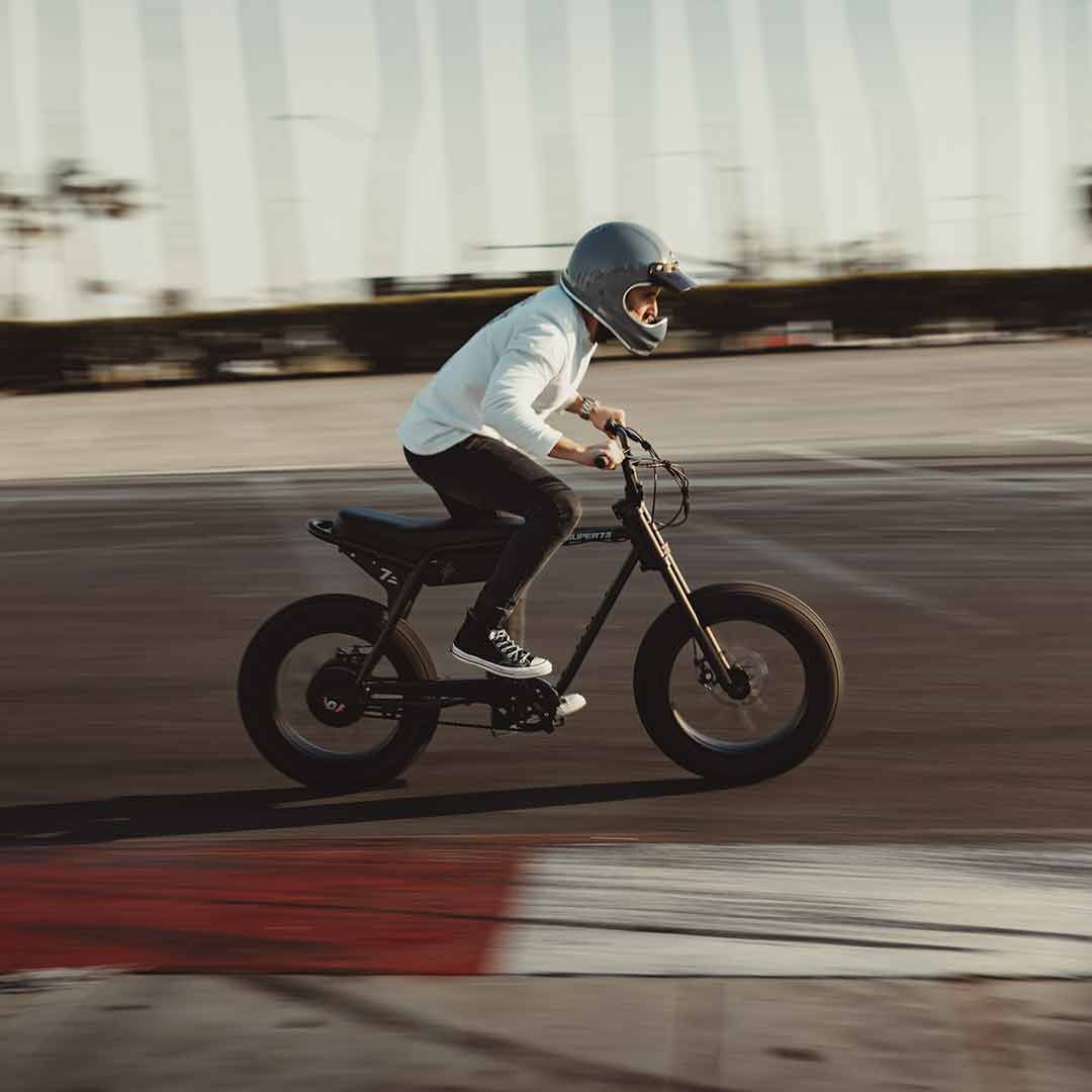 A young man zooming past the camera on a track on his super73 obsidian zx 