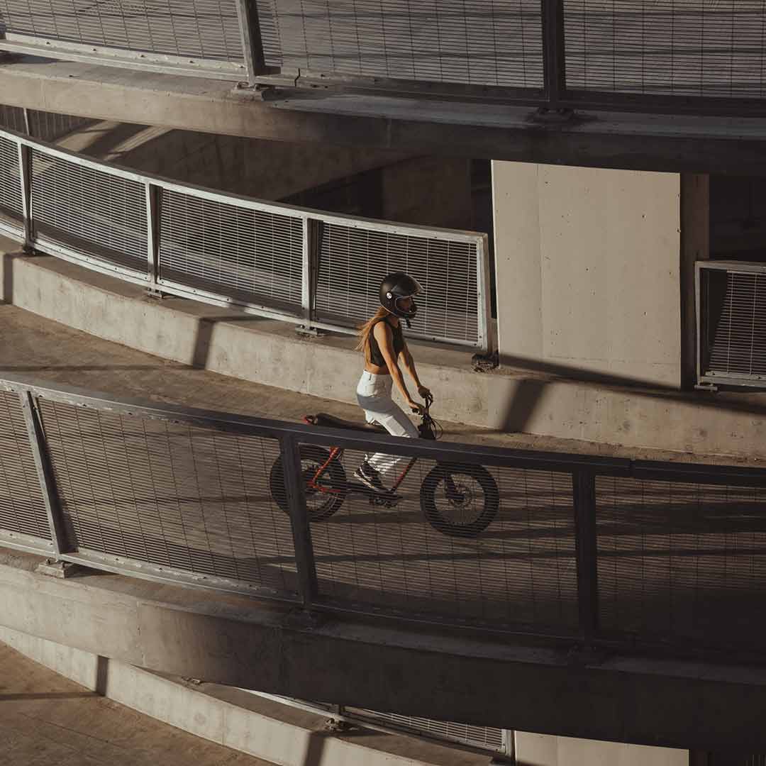 A young woman cruising down a spiral ramp during sunset on her super73 burgundy zx 